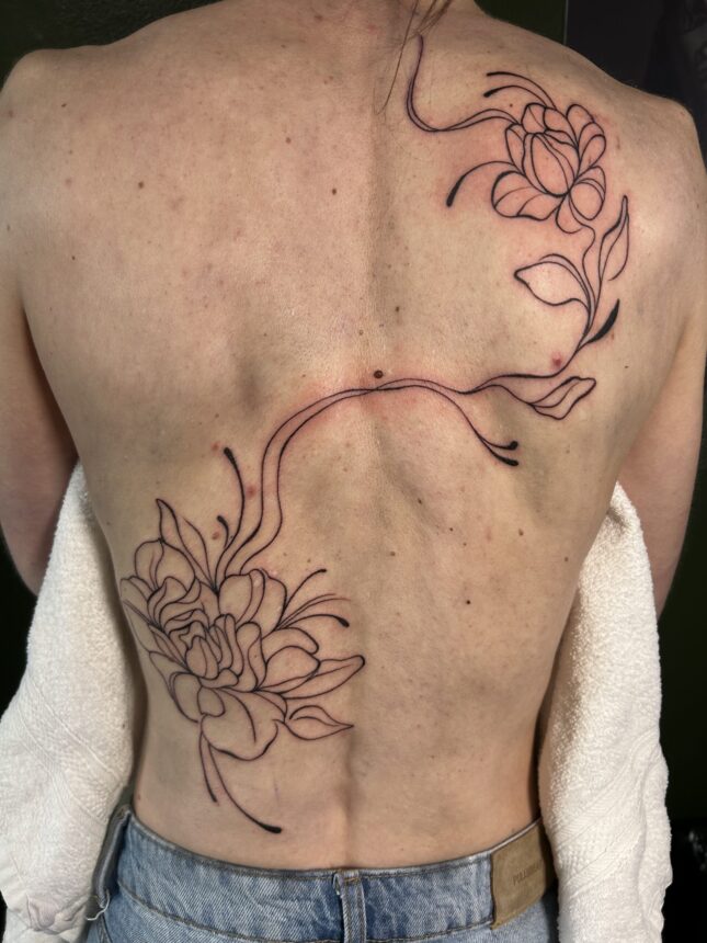 Stor blomster-tatovering langs rygsøjlen