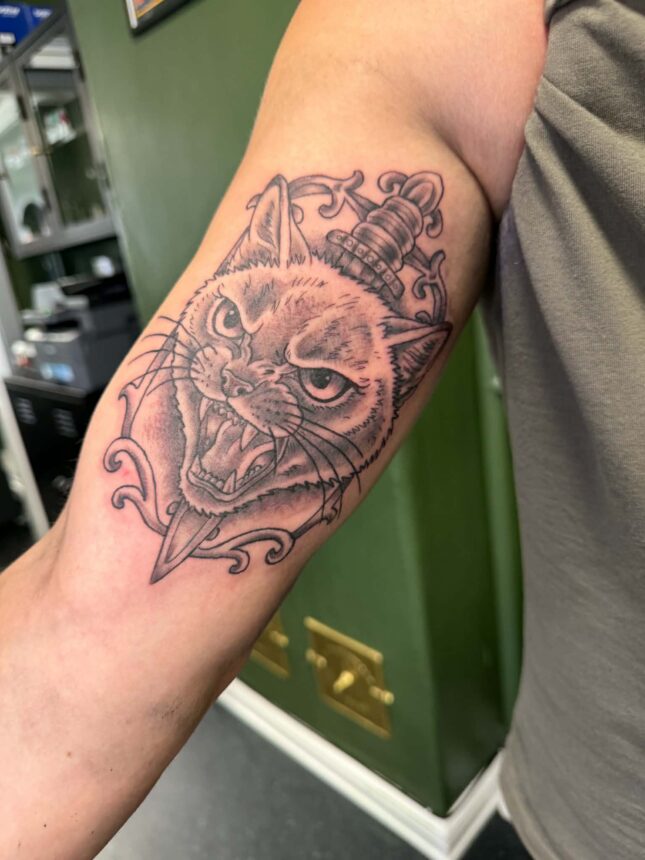 Tatovering af vred kat med dolk på underarm